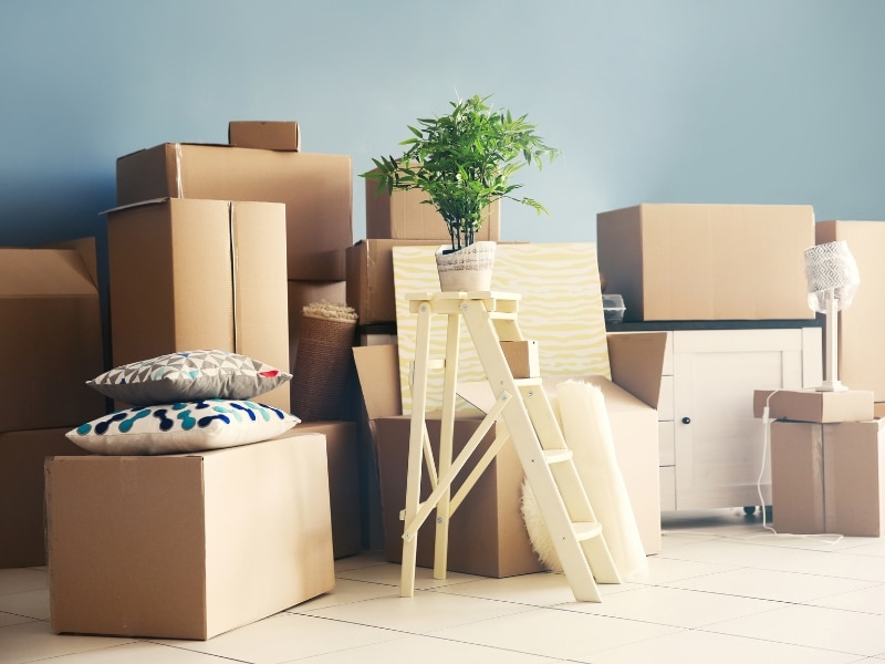 Stacked cardboard boxes, ladder and household items during clearing house after death preparation phase.